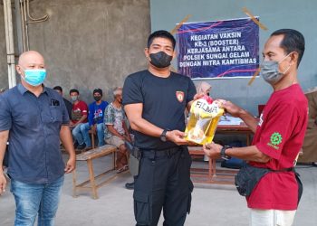 Kapolsek Sungai Gelam saat memberikan bonus 2 liter minyak goreng kepada warga yang mengikuti vaksinasi ke 3 (foto: GA)