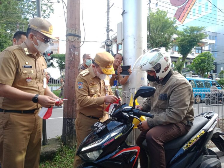 Al Haris saat memberikan bendera Merah Putih kepada pengendara yang melintas di Simpang IV Bank Indonesia (foto: ist)